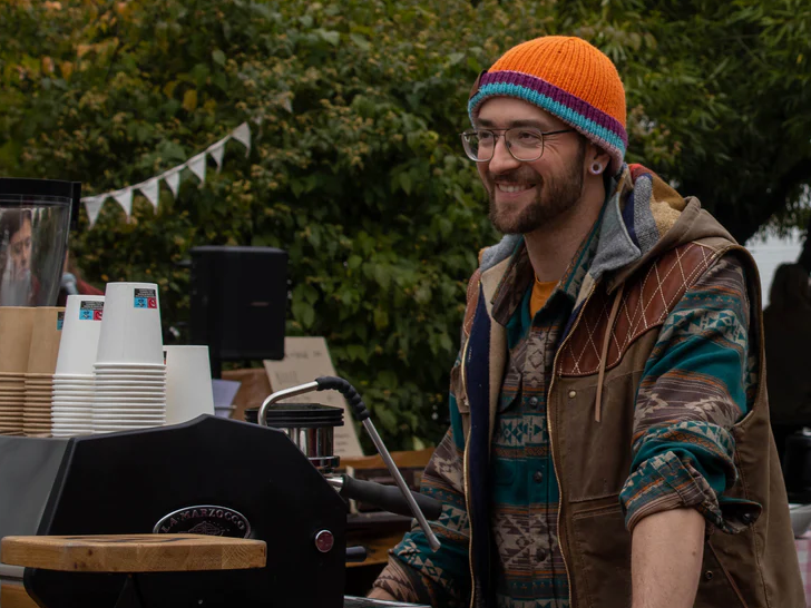Bild som visar barista Grant Reimer från Stoked Coffee vid sin kaffebar.