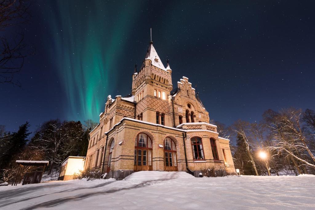 Merlo Slott i vinterlandskap, mörk himmel med norrsken i bakgrunden