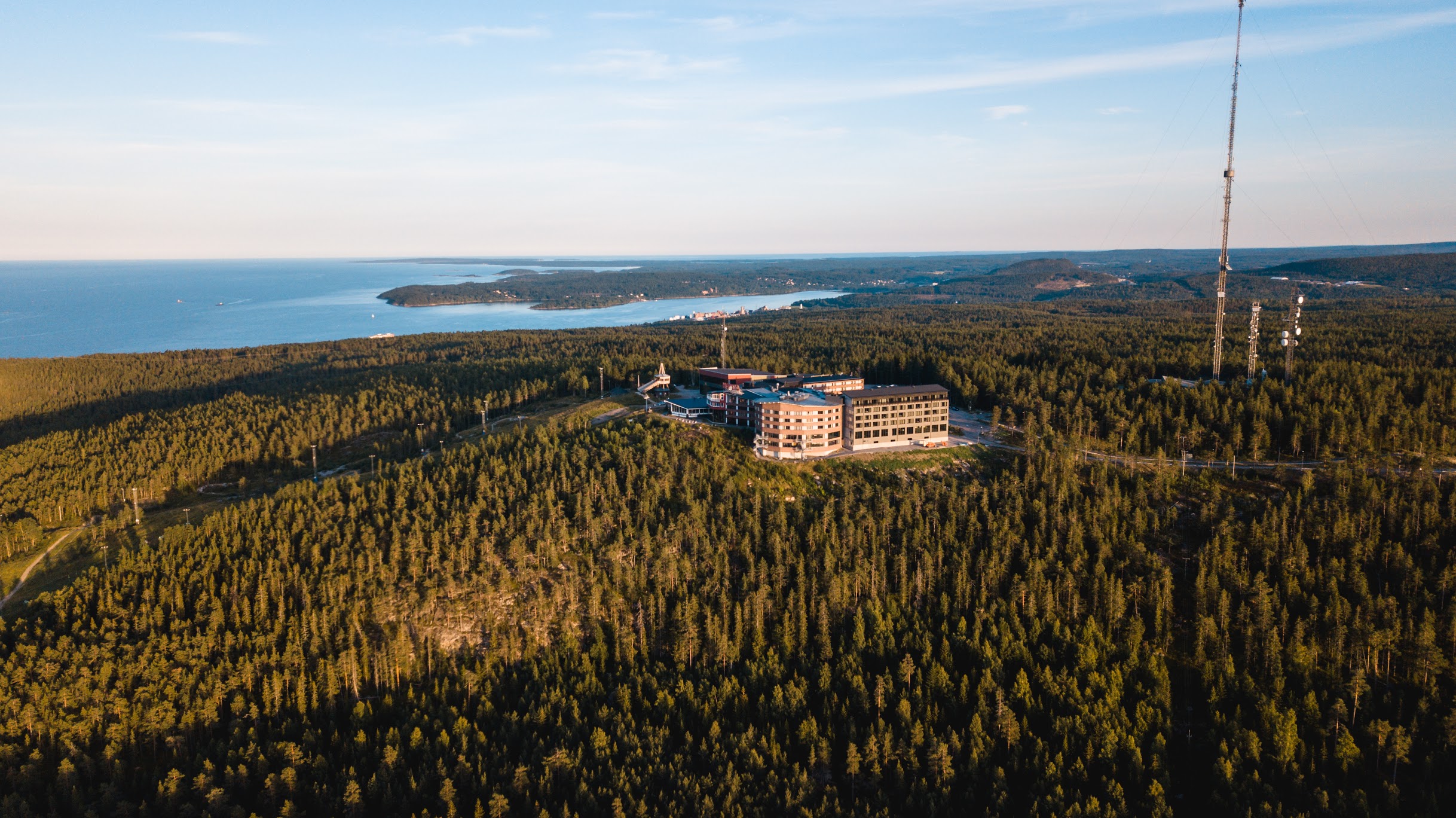 Drönarbild över Södra Berget i Sundsvall med Hotell Södra Berget som ligger på bergets topp och havet i bakgrunden.