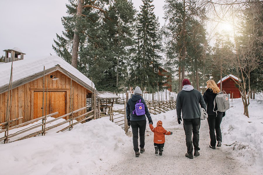 En familj promenerar längs en vintrig gångväg. De passerar en gammal lada.