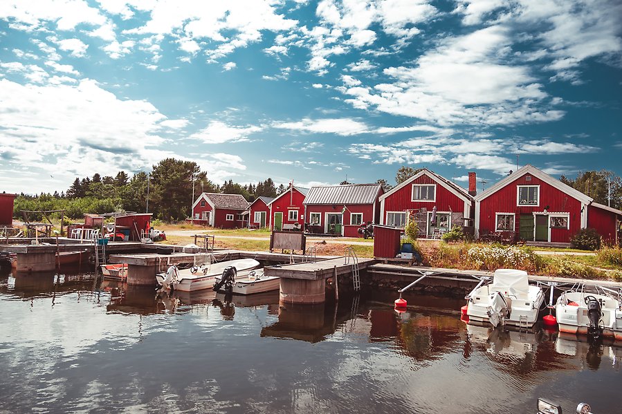 Båtar anlagda vid brygga med röda sjöstugor