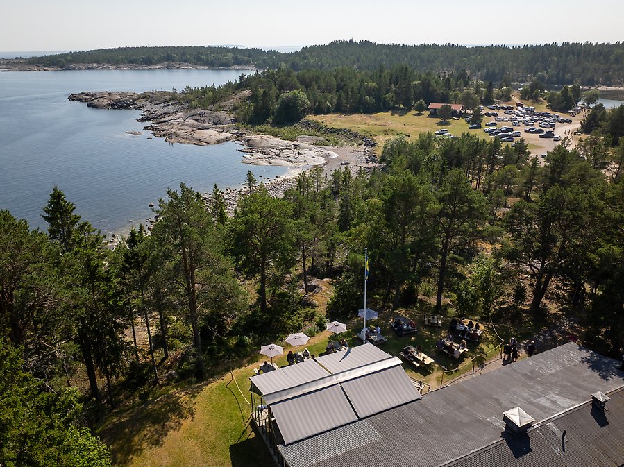 Stuga omringad av träd med vacker havsutsikt och klippor.