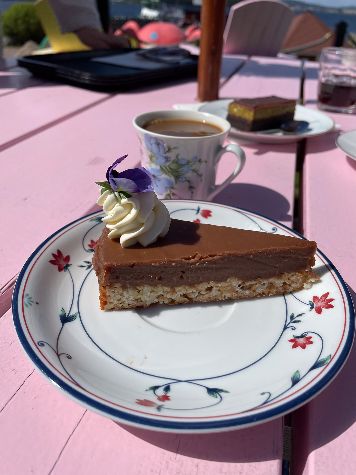 Bit av chokladtårta på assiett på rosa bord