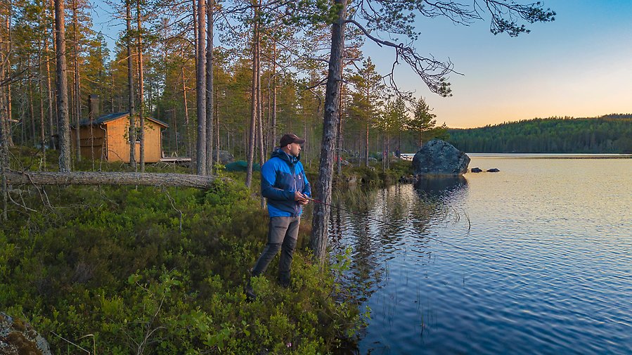 Man står vid sjö och fiskar.