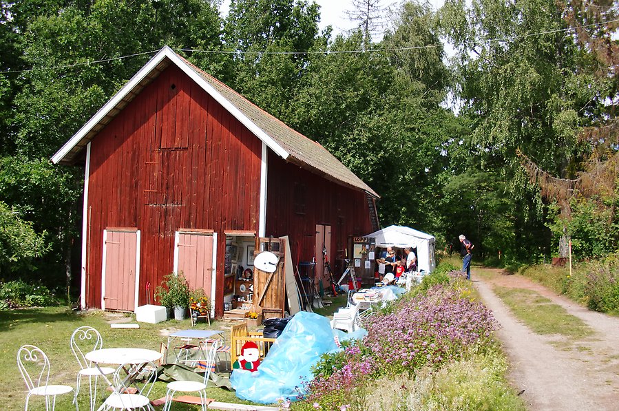 Ett gammalt rött uthus med möbler och andra grejer ståendes utanför
