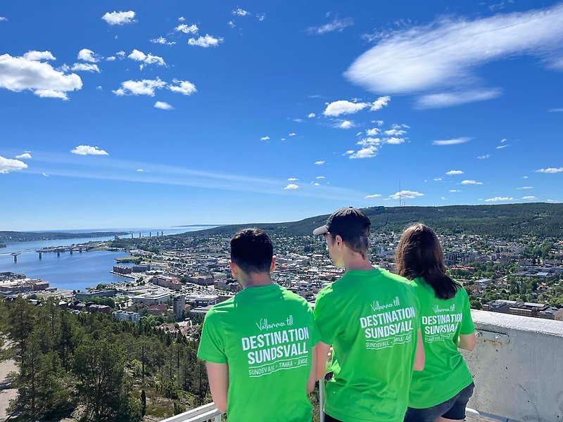 bild av tre ungdomar med gröna t-shirts som står i ett utsiktstorn och ser ut över Sundsvall.