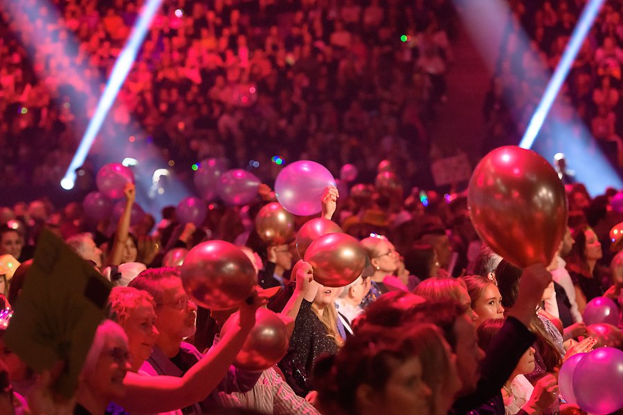 Publik som sitter och håller upp ballonger i luften på Melodifestivalen