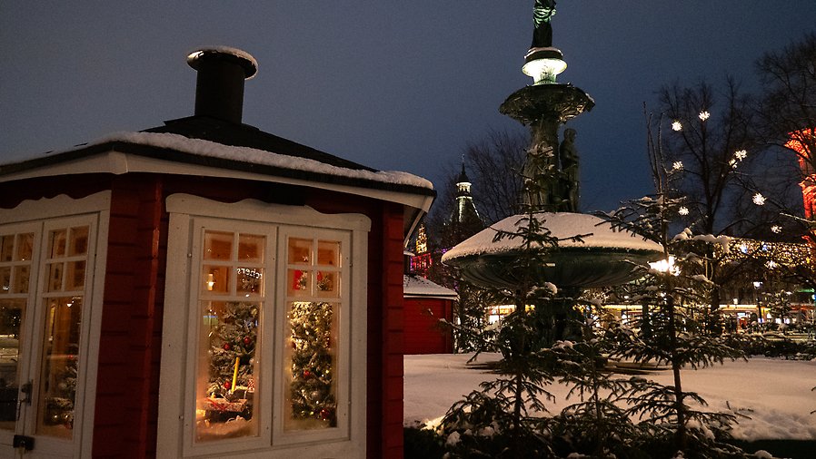 Röd liten stuga framför snötäckt fontän i Vängåvan i Sundsvall.