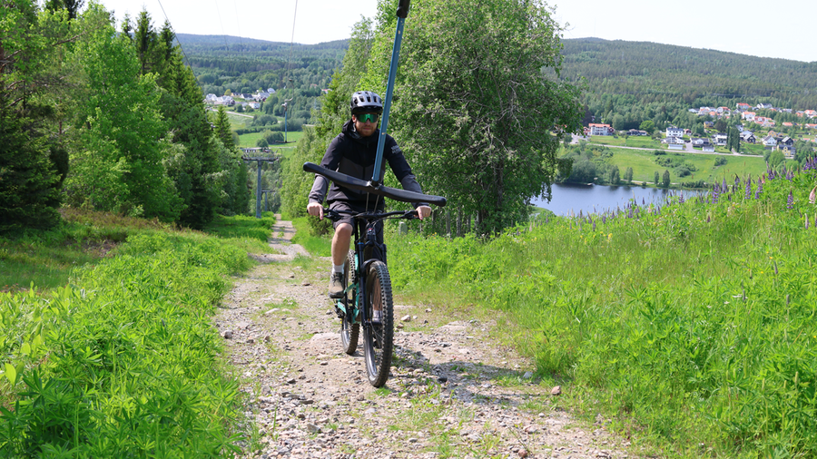 Bild som visar cyklist som åker lift upp med cykel i Sidsjöbacken på Södra Berget i Sundsvall.