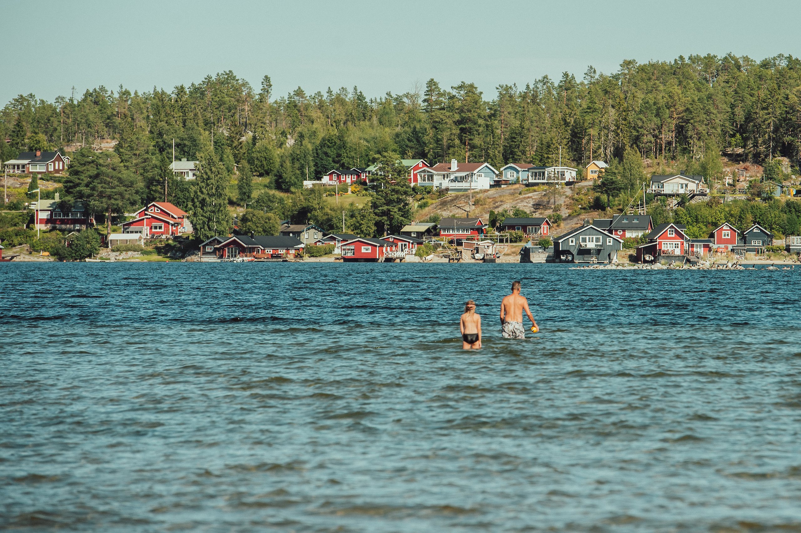 En man och ett litet barn badar tillsammans i havet